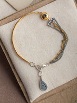 Gold and silver Comet bracelet with charms on a beige fabric background handmade by Leeloobird Jewelry in Bali