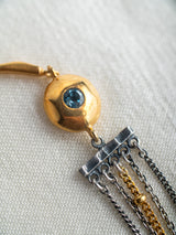 Gold and silver bracelet handmade by Leeloobird Jewelry bali with a blue gemstone pendant on a textured white background