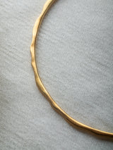 Gold and silver bracelet handmade by Leeloobird Jewelry bali with a blue gemstone pendant on a textured white background