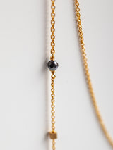 Gold chain necklace Leeloobird with a black bead on a light gray background