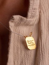 A gold vermeil Angelito necklace handmade by Leeloobird Jewelry Bali with a square-shaped medallion pendant, displayed on a textured fabric.