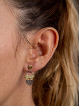 Gold and silver earrings trust model with chain details on right hear.