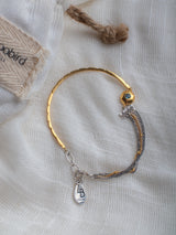 Gold and silver bracelet handmade by Leeloobird Jewelry bali with a blue gemstone pendant on a textured white background
