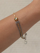 Gold and silver Comet bracelet with charms on a beige fabric background handmade by Leeloobird Jewelry in Bali