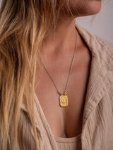A gold vermeil Angelito necklace handmade by Leeloobird Jewelry Bali with a square-shaped medallion pendant, displayed on a blond female model.